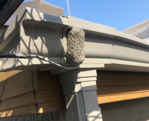 葛飾区新小岩で、ローラーを使って雨樋に上塗り塗装を施している様子