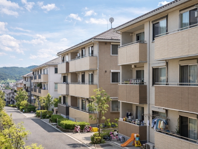 東京都多摩エリアの低層ファミリー向け賃貸アパート外観。子ども用自転車や遊具が見られる住宅街で、良好に維持管理された建物の様子。